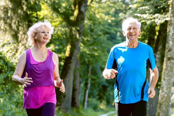 Twee senioren joggen in een bos